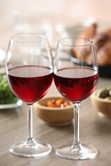 Naklejka premium Red wine and delicious dinner served on wooden table, closeup