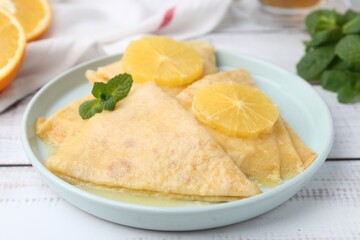 Delicious Crepes Suzette on white wooden table, closeup