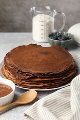 Delicious chocolate crepes with sweet paste and blueberries on light grey table, closeup