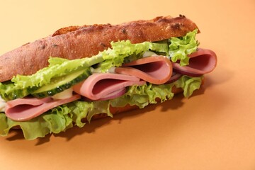 Baguette sandwich with ham on orange background, closeup