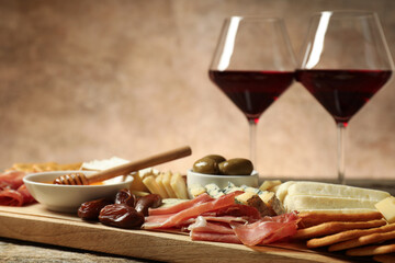 Different types of delicious cheese, other snacks and wine on table, closeup