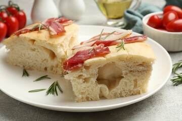 Pieces of delicious focaccia bread with bacon served on grey table, closeup