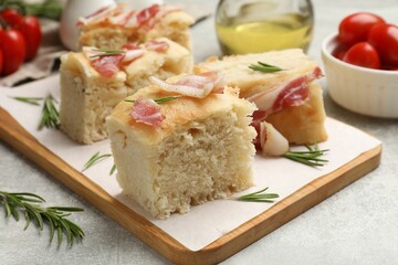 Pieces of delicious focaccia bread with bacon served on grey table, closeup