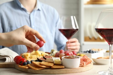 Women enjoying different snacks and wine during brunch at light grey table indoors, closeup
