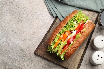 Delicious baguette sandwich with tomatoes and yellow beans on grey textured table, top view. Space for text