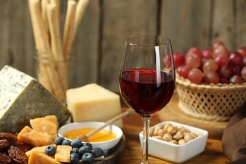 Red wine and different snacks served on table, closeup