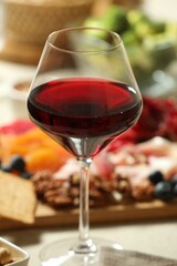 Red wine and different snacks served on table, closeup
