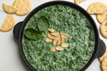 Delicious spinach sauce with peanuts and crackers on white table, flat lay