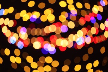 Blurred view of colorful lights on black background, bokeh effect