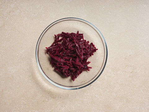 Shredded beets are placed in a bowl, highlighting a crucial step in making traditional Ukrainian beetroot soup. This colorful ingredient enhances the dish's flavor and richness
