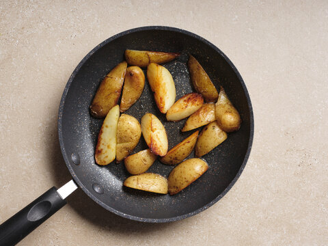 Freshly cut golden-brown potatoes are being saut&eacute;ed in a frying pan, showcasing the cooking step for a delicious Ukrainian beetroot soup recipe. Perfectly enhanced flavors await
