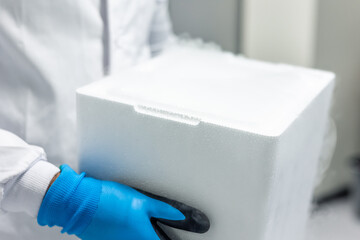 Scientist carrying frozen samples in styrofoam box in laboratory