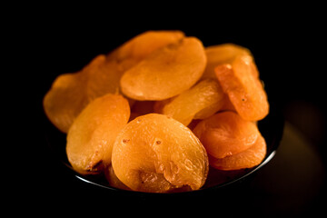 Close-up of dried apricots on a plate showcasing rich texture against a dark background
