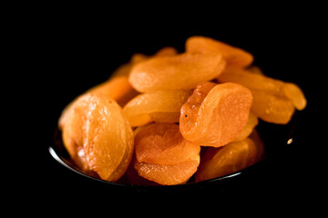 Dried apricots on a black plate showcasing their rich texture and vibrant color in a close-up view