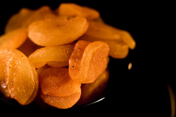 Close-up view of dried apricots on a plate showcasing texture and color against a black background