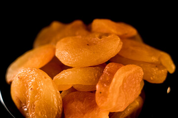 Close-up view of dried apricots on a plate against a black background showcasing rich textures and vibrant colors