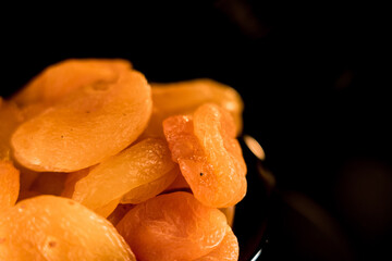 Close-up view of dried apricots arranged on a plate against a dark background showcasing their texture and color