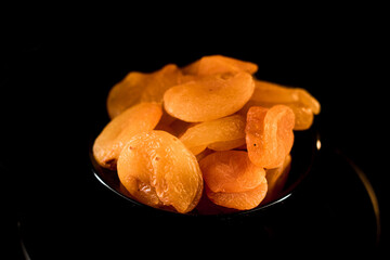 Dried apricots arranged beautifully on a plate against a black background showcasing their vibrant color and unique texture