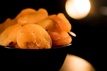 Close-up view of dried apricots showcasing texture on a black plate with warm lighting