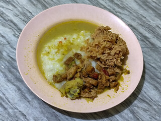 Chicken porridge is a common breakfast menu in Indonesia, served with coconut milk sauce.