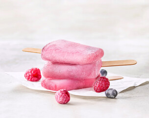 Lody owocowe z malinami i jagodami na tle jasnego tła w ciepłej scenerii © Jolaya