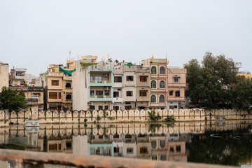 Obraz premium Wohnhäuser am See an einem bewölkten Tagin Udaipur in Rajasthan Indien