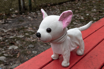 Toy plush dog on a dirty bench in the park
