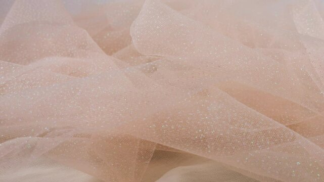 Pleats of delicate airy organza in pink tones rotate on the showcase. The theme of a wedding, bride, dress, fashion.