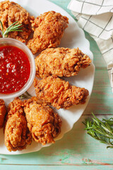 Close-up of a plate of delicious homemade golden brown crispy fried chicken wings with hot sauce © V