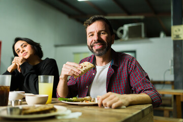Happy man savoring tasty tacos at a taqueria, dining with friends in a relaxed and genuine mexican environment