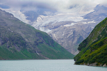 Kaprun high mountain reservoirs, Stausee Mooserboden coastline - cloudy summer day, August 20, 2024. Mountains, glacier, water reservoir  under the rainy cloudy sky but nice view before the storm.