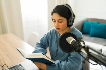 Content creator immersed in reading a book while recording audio for her engaging online podcast...