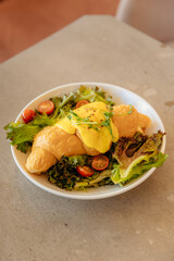 Croissant topped with cream with herbs and vegetables for breakfast. Healthy dish in a restaurant. Vegan croissant on a plate