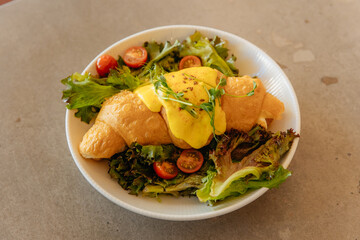 Croissant topped with cream with herbs and vegetables for breakfast. Healthy dish in a restaurant. Vegan croissant on a plate