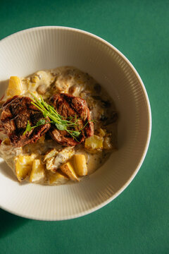 Veal medallions with potatoes and mushrooms in a plate on the table. Healthy food side dish