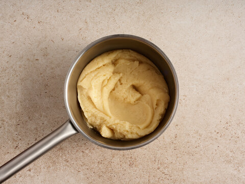 Smooth and creamy mashed potatoes sit in a stainless steel pot on a light countertop. Perfectly prepared, they are ready to complement any hearty meal