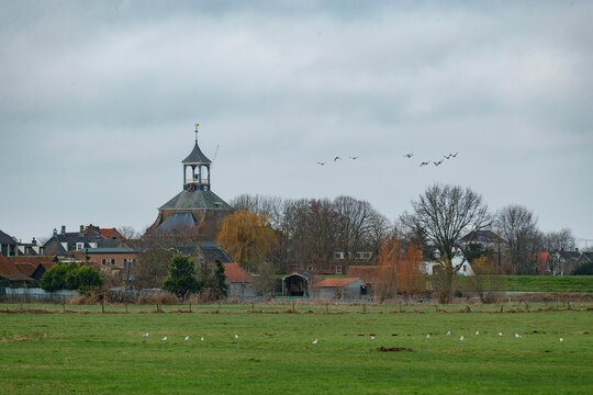 Historic charm of dorp hoge zwaluwe showcasing the iconic church and serene rural landscape under a cloudy sky