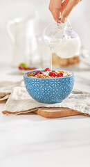 Miska płatków śniadaniowych z owocami i mlekiem na jasnym blacie kuchennym © Jolaya