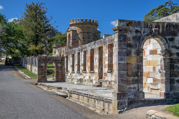 Historic stone building with arches and tower in Port Arthur, Tasmania, Australia, under a bright blue sky © Elena Pochesneva