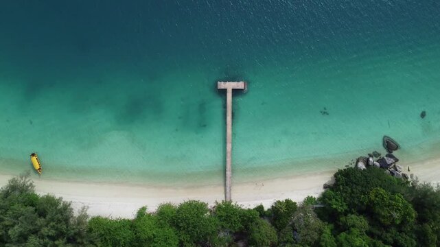 Aerial footage of a wooden pier on a sandy beach on a sunny day in the Perhentian Islands, Malaysia