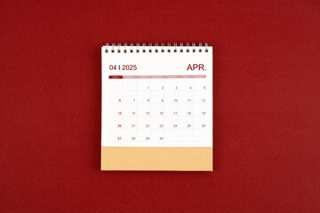 April 2025 desk calendar on red leather.