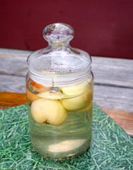 In einem Glas mit Deckel im Wasser befindliche Äpfel.
