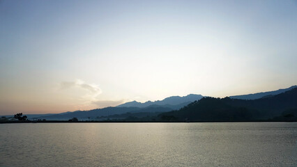 Fototapeta premium Peaceful Lakeside Sunset Over Mountain Silhouettes Under a Serene Sky