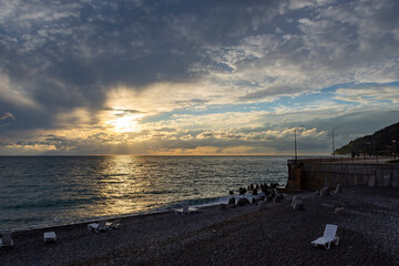 Dramatic sky with dark clouds on calm sea at sunset. Black Sea coast, early autumn. Deserted beach. Beach loungers