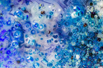 Intricate close-up of shimmering beads and dynamic swirls in hues of blue and purple, creating a mesmerizing interplay of texture and light.