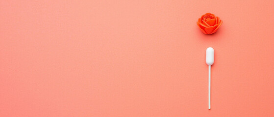 Orange rose and white tampon on peach background