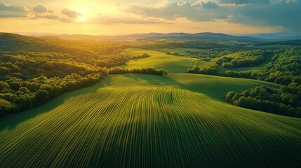 Obraz premium Golden Hour over Rolling Hills and Green Fields creating a majestic landscape with a sun setting sky