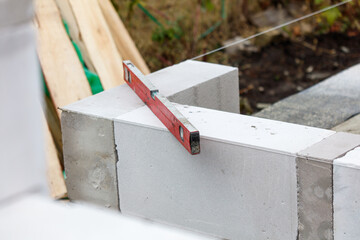 A red level is laying on a white brick wall