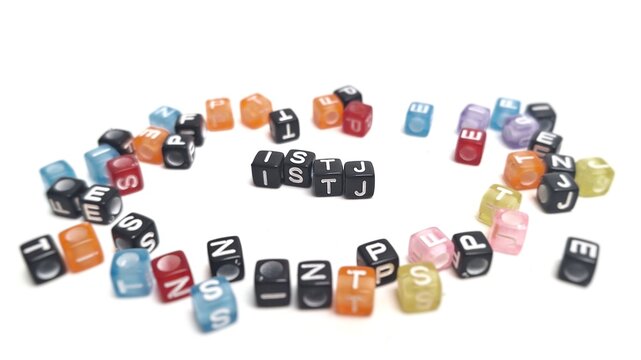 Scattered colorful plastic cubes, focus on the letters ISTJ in the center. The foreground and background are blurred. ISTJ is one of the 16 personality types identified by the MBTI test - Powered by Adobe