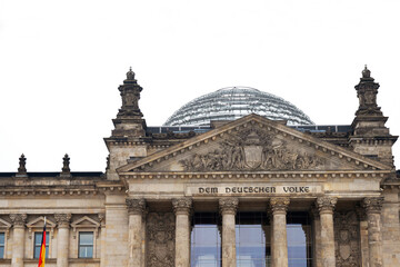 Obraz premium Front view of iconic Reichstag parliament building with glass dome in Berlin, Germany. Bundestag, with inscription Dem Deutschen Volke, symbolizing german unity and democracy. Copy space